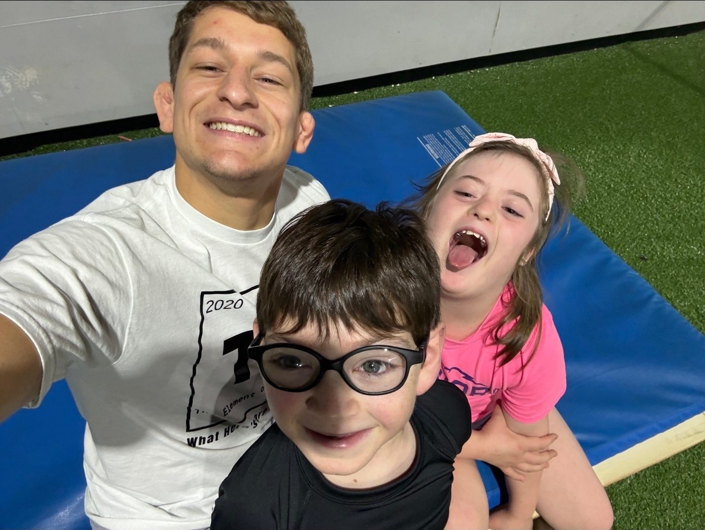 Drake on the mat with two of his young athletes