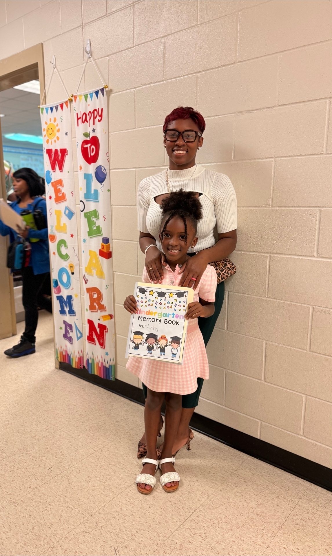 Dyimond with her daughter holding a kindergarten memory book