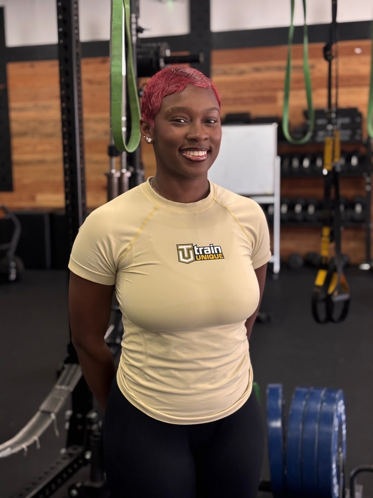 Coach Dyimond in a yellow Train Unique shirt, smiling on the Baton Rouge floor