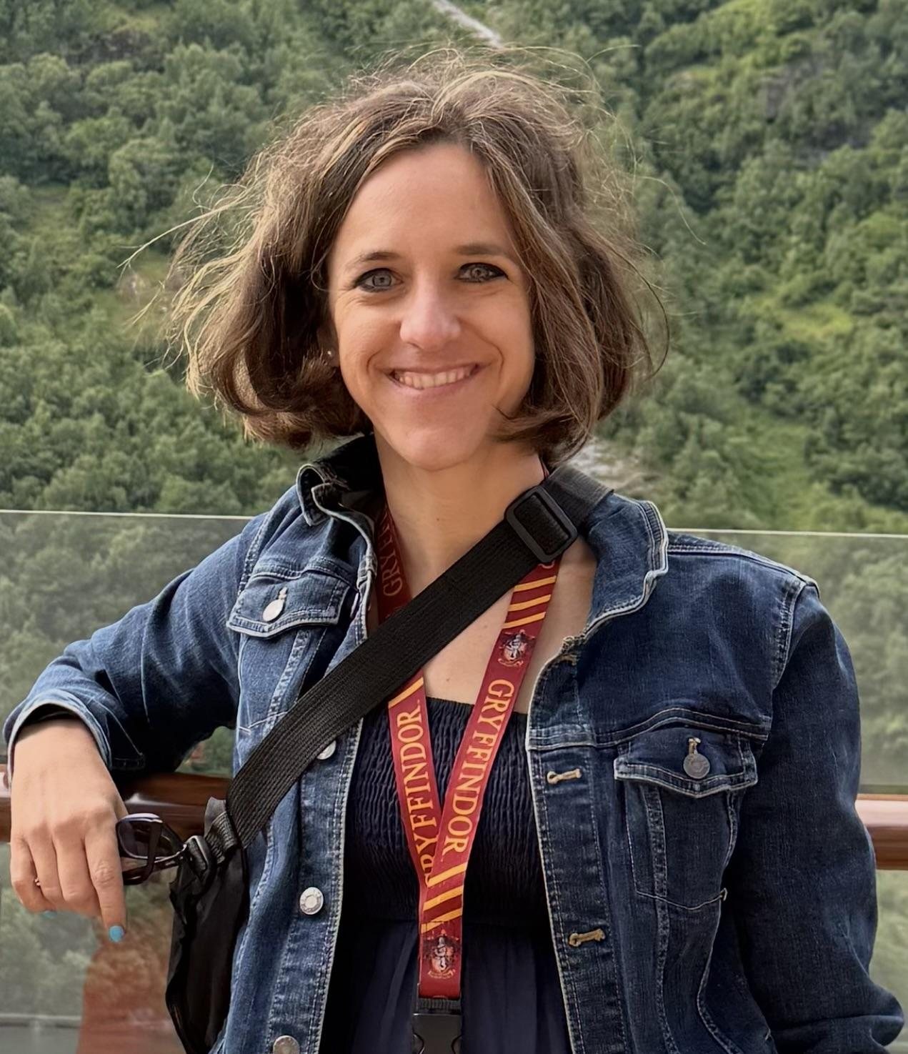 Coach Elizabeth in a denim jacket, smiling, green hills behind her