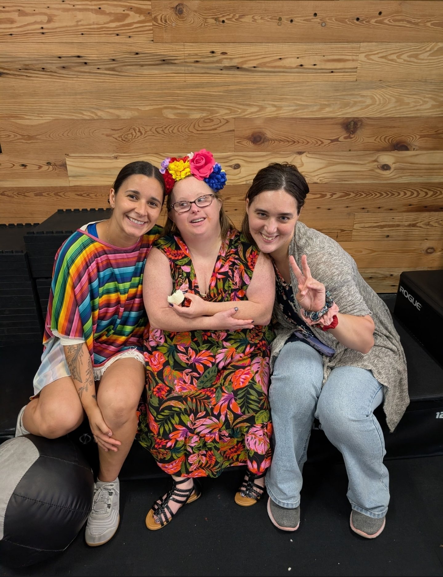 Madison in a striped poncho with two friends at a fiesta on the floor, one in a flower crown