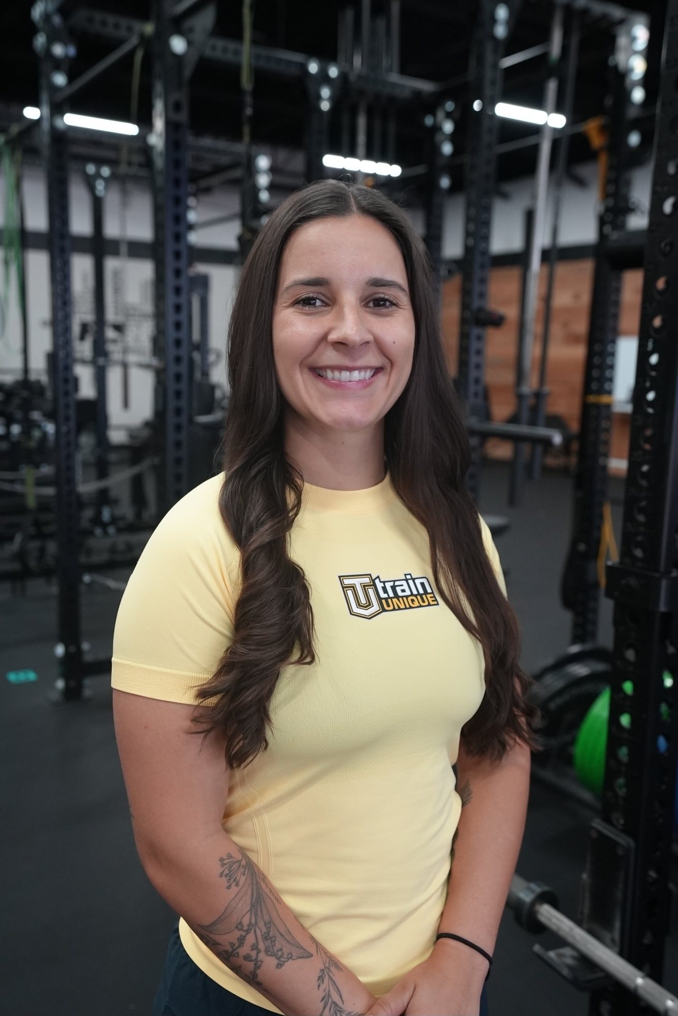 Coach Madison in a yellow Train Unique shirt, smiling on the Baton Rouge floor