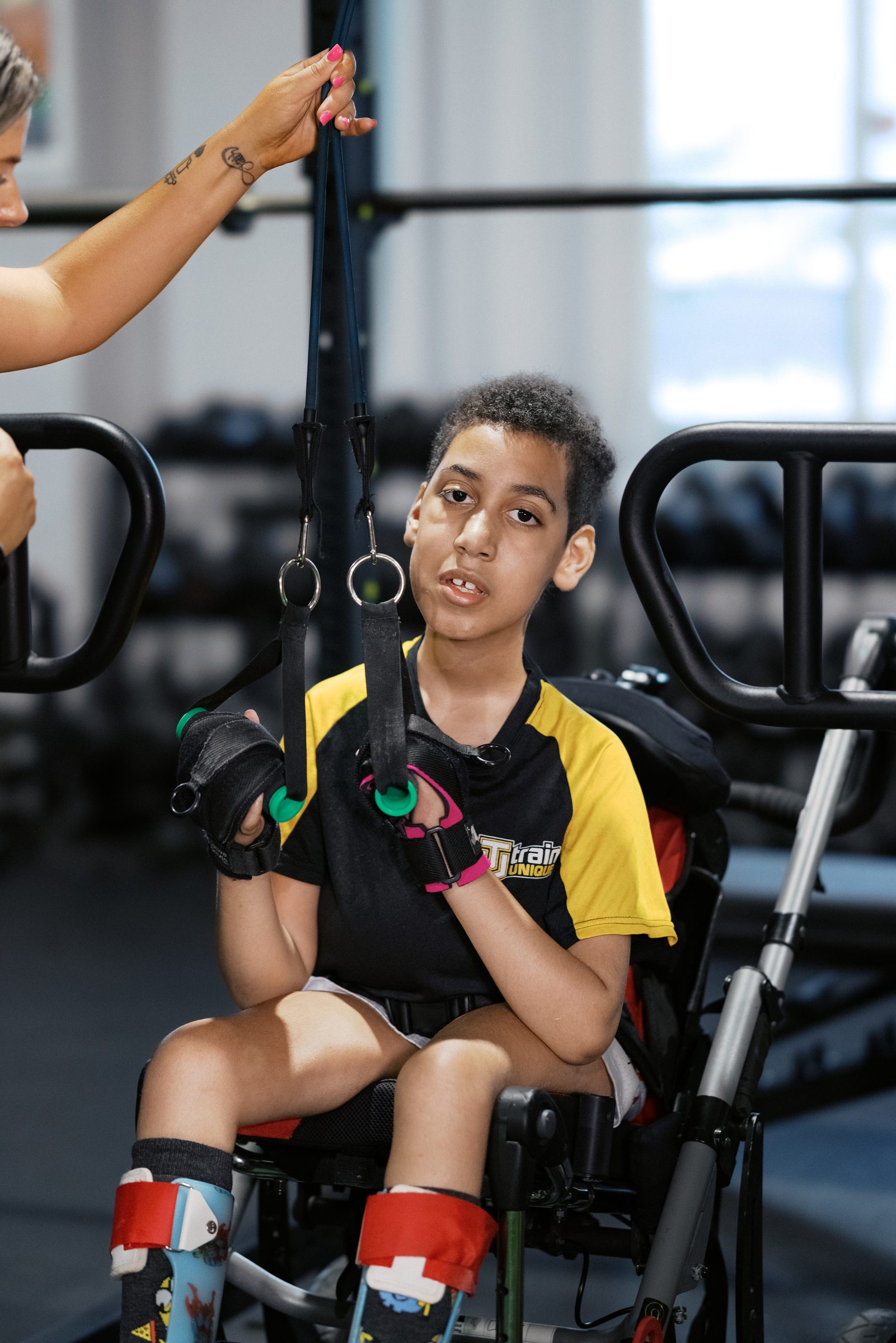 A young athlete in his adaptive chair reaching for the rings